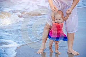 Ten months baby girl on the beach first time with mother. Infant feeling worry and excited playing on the beach. Mother hold