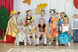 Ten small children and adult woman dressed in carnival costumes