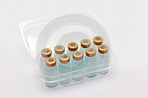 Ten vaccine bottles inside opened translucent plastic box