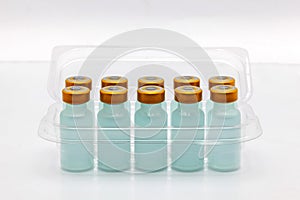 Ten vaccine bottles inside opened translucent plastic box