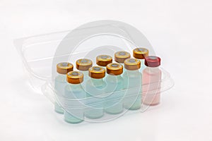 Ten vaccine bottles inside opened translucent plastic box with a different one