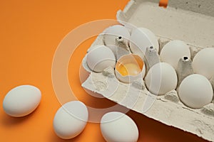 Ten white eggs in a carton package. Cardboard egg box on orange background