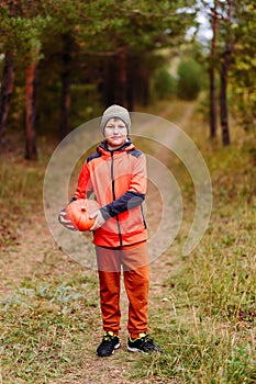 A ten-year-old boy in full growth and an orange red pumpkin. harvest