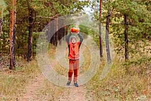 A ten-year-old boy in full growth and an orange red pumpkin. harvest