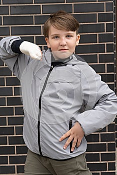 A ten-year-old boy in a gray jacket with a cast on his arm