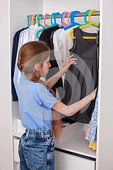 A ten-year-old girl chooses clothes in the closet.