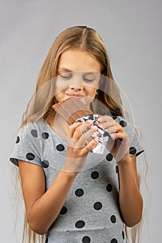 The ten-year-old girl joyfully looks at a chocolate bar