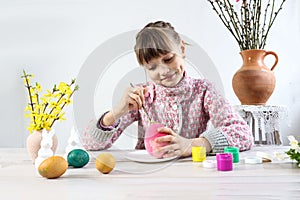 Ten year old girl paints Easter egg, light background