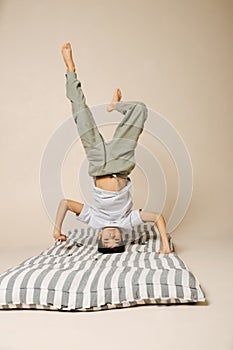 Ten year old indian boy standing on his head on a striped mattress