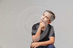 Ten- years boy looking up, daydream. Isolated on the gray background