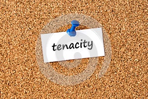 Tenacity. Word written on a piece of paper, cork board background