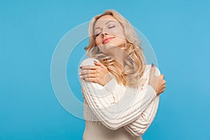 Tender beautiful blond woman embracing herself closing eyes, calming and comforting, self care, egoism