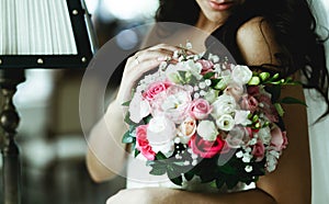 Tender bride touches a pink wedding bouquet standing in the hotel