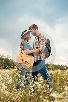 tender couple in love with backpacks in summer field