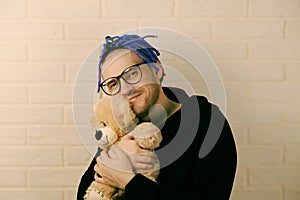 The Tender Embrace: A Man with Dreadlocks with Glasses Cherishing a Plush Toy