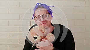 The Tender Embrace: A Man with Dreadlocks with Glasses Cherishing a Plush Toy