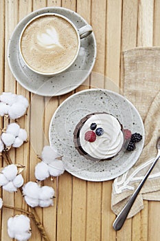 Tender french cupcake with cup of coffee outside. Atmospheric cotton decoration. Cozy breakfast at the terrace, guilty