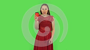 Tender girl in red dress drinking unpalatable coffee and is disgusted. Green screen