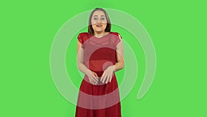 Tender girl in red dress is looking with tenderness smile. Green screen