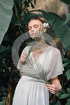 tender girl in white summer dress posing with tropical