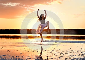 Tender girl young ballerina in pink transparent in a graceful jump on the lake