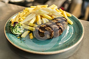 Tender grilled porterhouse steak served with crisp golden French fries and fresh green herb salad by BBQ or herb butter