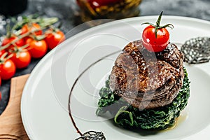 Tender lean medium rare beef fillet steak medallions with one sliced through to show the red meat with spinach, Restaurant menu,