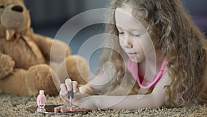Tender little girl painting nails with polish, kid dreaming to grow up soon