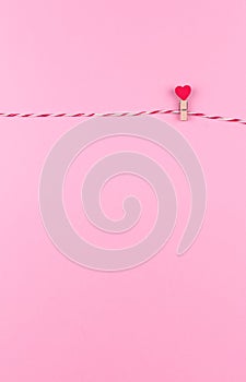 Tender little heart symbol of St. Valentine`s day on a clothespin and string creative postcard, copy space, flat lay.