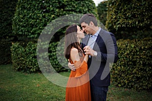 Tender love story of beautiful woman in orange dress and man in stylish suit