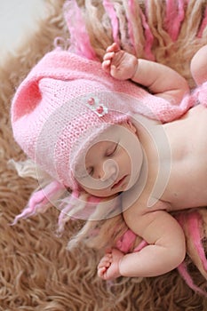 Tender newborn baby in pink cap sleeps stretching