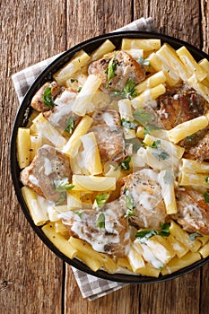 Tender pasta Tortiglioni with chicken in a spicy creamy sauce with herbs close-up in a plate on the table. Vertical top view