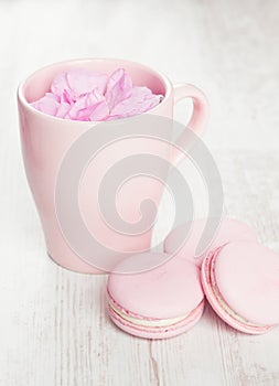 Tender pink macaroons and tea cup on white wood background