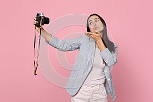 Tender pretty young woman doing selfie shot on retro vintage photo camera, blowing sending air kiss isolated on pink