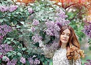 Tender and romantic brunette girl in lilac garden, eyes closed. Nature and spring. Dream concept.