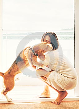 Tender scene on sunny terrace: beagle dog kisses its owner. Pets at home concept image