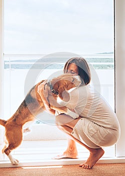 Tender scene on sunny terrace: beagle dog kisses its owner