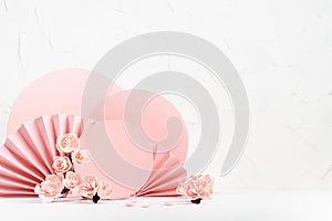 Tender spring floral background in japanese style - pink sakura flowers, petals, pink circles, paper fans on white table as stage.