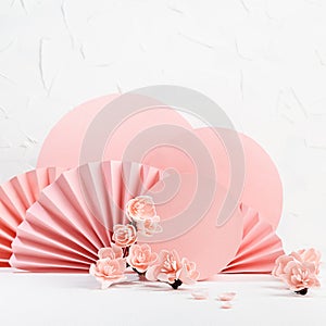 Tender spring floral background in japanese style - pink sakura flowers, pink circles, paper fans on white table as stage.