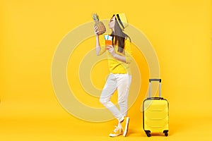 Tender traveler tourist woman in hat holding passport tickets, kissing pineapple fruit isolated on yellow orange