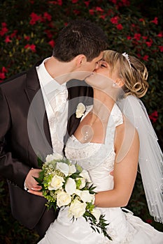 Tender wedding kiss red roses