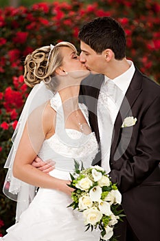 Tender wedding kiss red roses