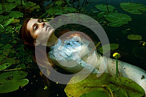 Tender young woman swimming in the pond among water lilies