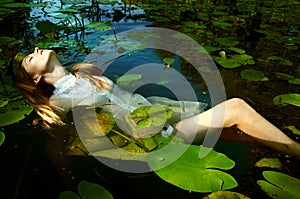 Tender young woman swimming in the pond among water lilies