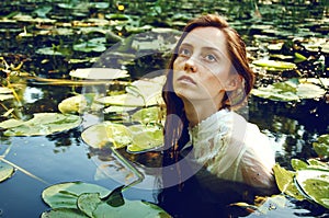 Tender young woman swimming in the pond among water lilies