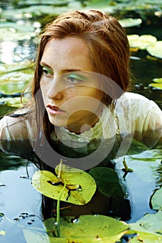 Tender young woman swimming in the pond among water lilies