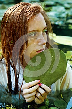 Tender young woman swimming in the pond among water lilies