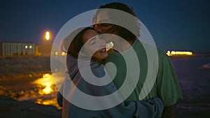 Tender youngsters enjoy night ocean beach closeup. Gentle man kissing girlfriend