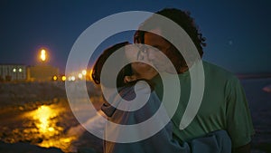 Tender youngsters enjoy night ocean beach closeup. Gentle man kissing girlfriend