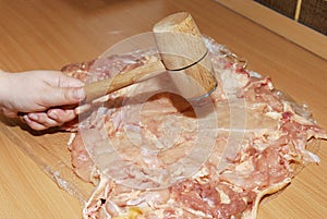Tenderizing the meat with mallet on the kitchen board